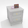 White Bedside Table With Two Drawers Gold Handles Pink Alarm Clock And Photo Frame
