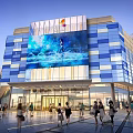 Modern Commercial Complex Featuring Large Digital Screen Blue White Square Facade And Vibrant Pedestrian Area