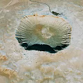 Aerial View Of Large Circular Meteor Crater In Desert Landscape With Central Depression And Surrounding Terrain