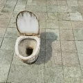 Dirty Stained Old Toilet Sitting On Stone Tiled Floor With Grime