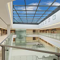 Shopping Mall Atrium With Glass Skylight Blue Sky White Clouds Multiple Floors Glass Railings Shops