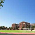 Red Brick School Buildings With Football Field Running Track And Trees In Clear Blue Sky