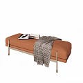 Orange Ottoman with Metal Legs and Gray Plaid Blanket on Top and Magazine