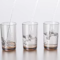 Three Transparent Glass Cups With Brown Base As Water Splashes In