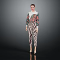 Woman In Colorful Printed Top And Pants Standing Stylishly Against Gray Background