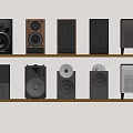 Various Design Speakers Collection Displayed On Wooden Shelf With Different Styles