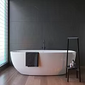 White Freestanding Bathtub With Dark Gray Marble Wall Black Shelf And Wooden Floor