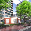 Modern High Rise Building Exterior Wall with Red Brick Design Surrounded by Trees and Pedestrians