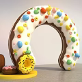 Dessert Shop Displaying Giant Ring Donut With White Frosting Colorful Candy Beans And Small Donuts