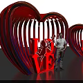 Vibrant Neon Heart Sculpture With LOVE Lettering And Cupid Design Featuring Person
