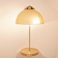 Golden Modern Table Lamp With Dome Shade And Round Metal Base On Light Wall
