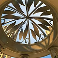 Ornate Circular Metal Ceiling With Leaf Patterns And Columns Against High Rise Buildings