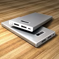 Silver Mobile Power Banks With USB Ports And Digital Displays On Wooden Tabletop