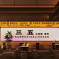 Cozy Bar Interior Featuring Wooden Tables Stools Plants Yellow Lighting And Signboard