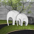 White Abstract Elephant Sculpture in Outdoor Garden With Green Grass And Gray Stone Wall