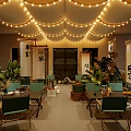Japanese Outdoor Restaurant Dining Space With String Lights Scroll Decorations Green Plants And Wooden Tables