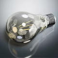 Transparent Light Bulb With Visible Filament And Textured Surface On Gray Background