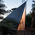 Unique Triangular Guesthouse Architecture With Sharp Metal Roof And Warm Lighting Surrounded By Trees