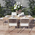 Outdoor Dining Table Set With Woven Chairs Hanging Lights And Green Plants On Wooden Deck