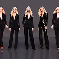 Five Women Wearing Black Suits Standing in a Row Against Gray Background