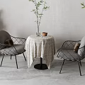 Round Table and Gray Cushioned Chairs with Black Metal Frames Tablecloth Vase Cup Green Plants
