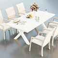 White Dining Table Set With Six Rattan Chairs Flower Arrangement Fruit Platter And Straw Hat