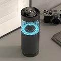 Black Cylindrical Electronic Appliance With Blue Circular Light And Grilled Top On Desktop