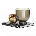 Golden Spherical Sculpture with Transparent Glass Vessel on Black Decorative Book