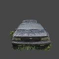 Abandoned Rusty Car With Open Hood Covered In Mud And Vegetation
