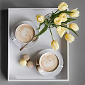 Two Latte Coffee Cups on White Tray with Yellow Tulips Vase and Macaron Desserts