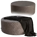 Round Gray Ottoman With Quilted Diamond Pattern And Black Blanket