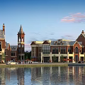 European Style Commercial Complex Featuring Clock Tower Red Brick Buildings Waterfront Reflection And Pedestrians
