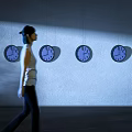 Walking woman passing by multiple clocks on wall with light and shadow effects