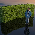 Green Curved Bush Hedge With Person Standing Beside Water Surface Reflection And Sunset Sky