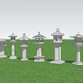 Multiple Traditional Stone Outdoor Lanterns Standing On Green Grass Field