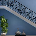 Ornate Staircase With Black Iron Railings Blue Wall Green Plant Black Vases And Pebble Decor