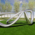 Silver Metallic Landscape Sculpture With Twisted Loop On Green Lawn And Trees Under Blue Sky