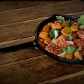 Savory Meat Chunks Sausages and Carrots in Cast Iron Skillet with Parsley on Wooden Table