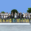 Outdoor Group Photo Of People In Formal Attire With Blue Sky Green Trees And Sign