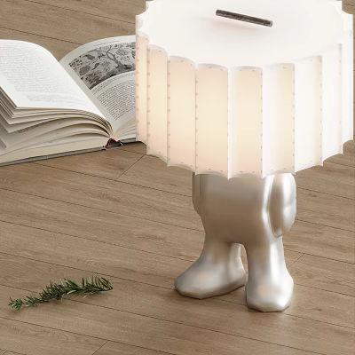 Table Lamp With Silver Humanoid Leg Base White Pleated Lampshade Near Open Book Wooden Floor 3d model