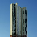 Modern High Rise Residential Building Exterior With Numerous Windows And Blue Sky Background