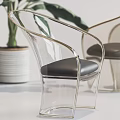 Transparent Leisure Chair With Gold Frame And Black Cushion Near Green Plant