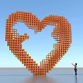 Giant Orange Heart Shaped Sculpture Constructed With Blocks And Person Standing Nearby