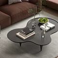 Modern Unique Shaped Black Coffee Table With Books Green Fruit Bowl Glass Vase And Plant