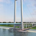 Grand Modern Suspension Bridge Spanning Wide River With Cruise Ships And Lush Riverside Landscape