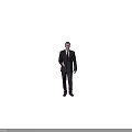 A Man In Dark Suit Standing Against Gray Background With Right Hand Extended For Greeting
