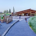 Visitor Center With Wooden Roof Sculptures Gravel Path Grass Area And People Walking