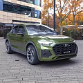 Green Audi SUV Exterior Design In Urban Setting With Modern Buildings And Trees