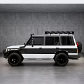 White and Black Off Road Vehicle With Roof Rack and Large Tires in Indoor Setting