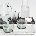 Assorted Glass Drinkware With Carafes On Marble Trays